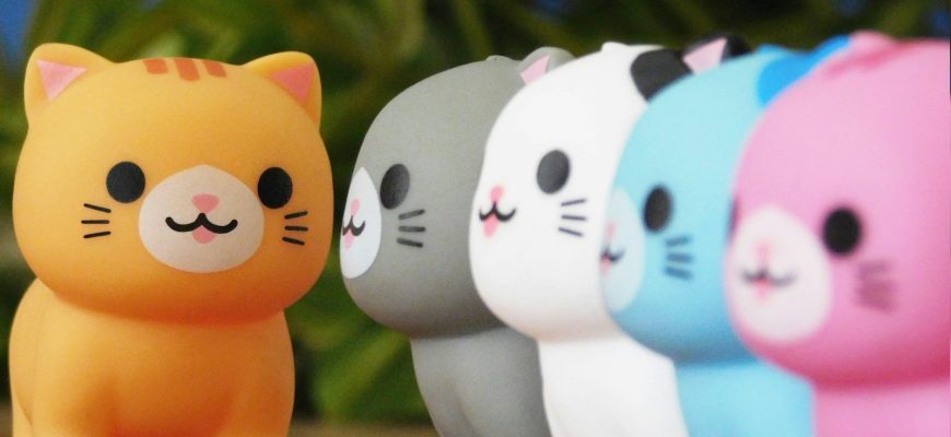 Row of colorful cat figurines with orange one in front