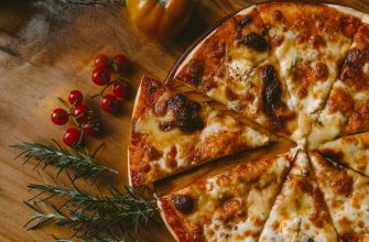 A sliced cheese pizza with cherry tomatoes and rosemary on a wooden board